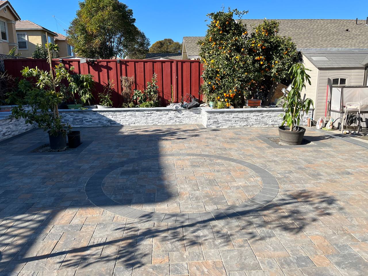 Backyard paver patio with circular accent and stacked stone planter